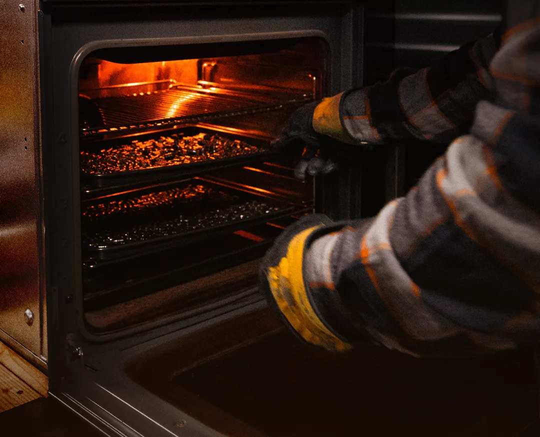 Worker placing trays of cast bullets into a heated curing oven, showing careful quality-controlled production.